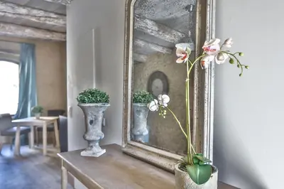 a mirror and a vase with flowers on a table at Apartments - Experience of PROVENCE in Gordes