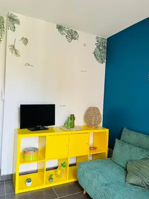 a yellow entertainment center with a tv and a couch at Un coin tropical en Provence ! in LʼIsle-sur-la-Sorgue