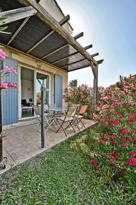 a patio with chairs and a table and flowers at LE PETIT BONHEUR - PLACE PARKING PRIVEE - CLiM - TERRASSE - PISCINE PARTAGEE - PROCHE PARC SPIROU in Saint-Saturnin-les-Avignon
