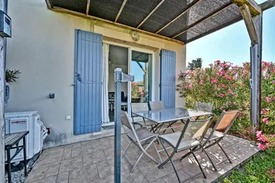a patio with a table and chairs on a patio at LE PETIT BONHEUR - PLACE PARKING PRIVEE - CLiM - TERRASSE - PISCINE PARTAGEE - PROCHE PARC SPIROU in Saint-Saturnin-les-Avignon