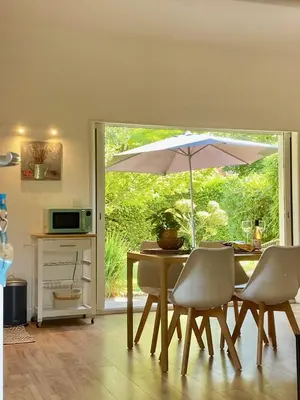 a dining room with a table with an umbrella at Appartement neuf et au calme proche Avignon in Althen-des-Paluds