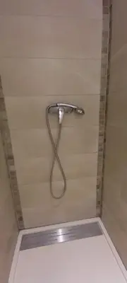 a shower with a hose attached to a wall at Logement lumineux, entièrement rénové avec jardin in Caumont-sur-Durance