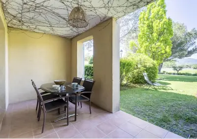 a dining room with a table and chairs and a yard at Hôtel du Golf de Pont Royal - appartement paisible rez de jardin - terrasse & piscine in Mallemort