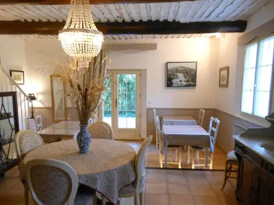 a dining room with a table and chairs and a chandelier at Les Passiflores in Roussillon