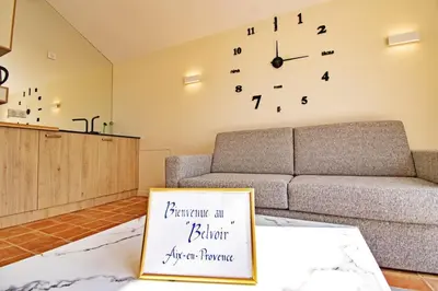 a living room with a couch and a clock on the wall at Appart13 piscine chauffée de luxe Belvoir13 à 10 min d Aix in Aix-en-Provence