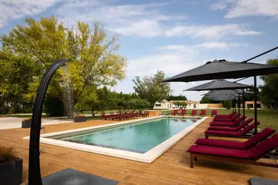 a swimming pool with chairs and umbrellas next to a pool at L'Insoupçonnée Saint Rémy de Provence by A Pinch Of Soul in Noves