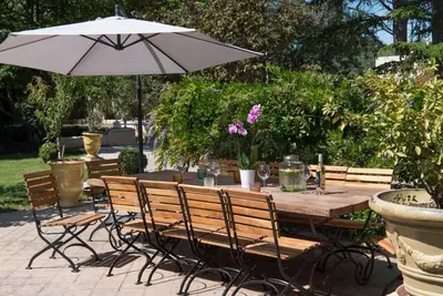 a wooden table and chairs with an umbrella at L'Insoupçonnée Saint Rémy de Provence by A Pinch Of Soul in Noves