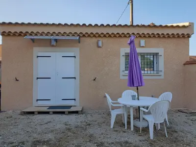 a table with chairs and an umbrella next to a building at Petite maison meublée entre Avignon et Carpentras in Morières-lès-Avignon