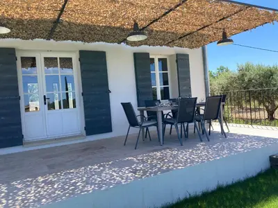 a patio with a table and chairs under a pergola at La bastide in Malemort-du-Comtat