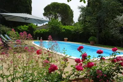 a swimming pool with pink flowers and an umbrella at The Blue Tit - private swimming pool in LʼIsle-sur-la-Sorgue