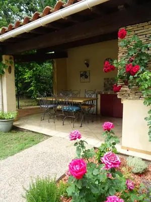 a patio with roses and a table and chairs at The Blue Tit - private swimming pool in LʼIsle-sur-la-Sorgue