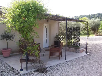 a pergola with two chairs and a bench in front of a house at OUSTAOU DU GAYET gîte de charme avec piscine privée in Lourmarin