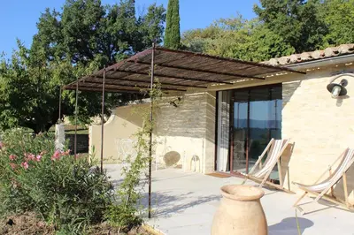 a house with two chairs and a pergola at Gîte Les Rapières in Gordes