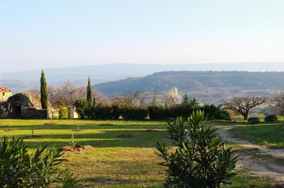 a dirt road in a field with trees and a house at Gîte Les Rapières in Gordes