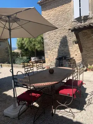 a wooden table with chairs and an umbrella at La Maison de la Forge in Gordes