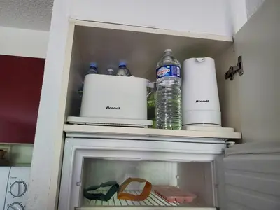 a cupboard with water bottles and other items in it at Les demeures du Ventoux in Aubignan