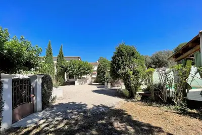 a courtyard with trees and a fence and a building at Maison Provençale avec piscine in Carpentras