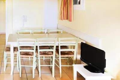 a dining room with a table and chairs and a tv at Village Pont Royal en Provence - maeva Home - Appartement 2 Pièces 7 Personnes Confort MAE-2253 in Mallemort