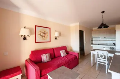 a living room with a red couch and a kitchen at Les Coteaux de Pont Royal en Provence - maeva Home - Appartement 2 Pièces 4 Personnes - Confort MAE-6002 in Mallemort