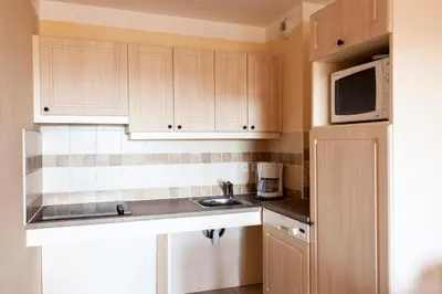 a kitchen with white cabinets and a sink and a microwave at Les Coteaux de Pont Royal en Provence - maeva Home - Appartement 2 Pièces 4 Personnes - Confort MAE-6002 in Mallemort