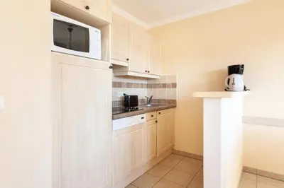 a kitchen with white cabinets and a microwave at Les Coteaux de Pont Royal en Provence - maeva Home - Appartement climatisé 2 Pièces 4 Personnes - Sélection MAE-6022 in Mallemort