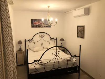 a bedroom with a black bed with a chandelier at Les Coteaux de Pont Royal en Provence - maeva Home - Appartement 4 pièces 7 personnes - Prestige - super Home MAE-2094 in Mallemort