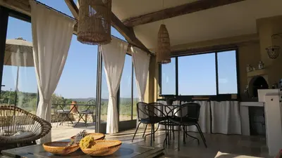 a kitchen with a table and chairs and large windows at Le Clos d'Estellan - Piscine chauffée in Bonnieux