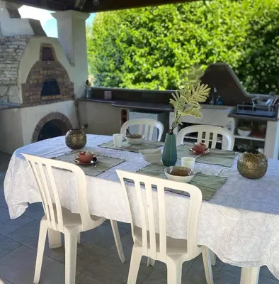 a table with white chairs and a table with a table cloth at Instant Parfait en Provence Chambre privée et piscine in Monteux
