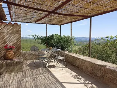 a patio with a table and chairs under a roof at Gite avec piscine 