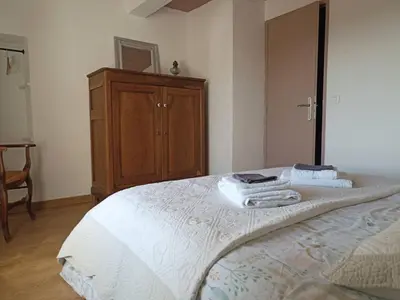 a bedroom with a large bed with a wooden cabinet at Gite avec piscine 
