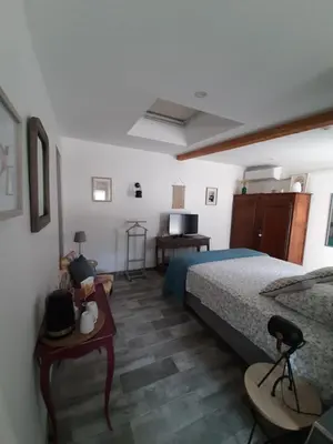 a bedroom with a bed and a desk and a television at La Colinière, Chambre d'hôtes in Aix-en-Provence