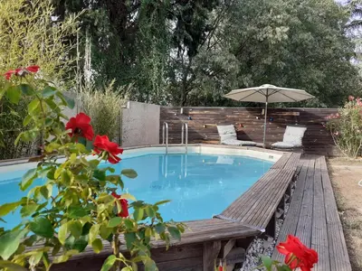 a swimming pool with a bench and an umbrella at Location saisonnière avec piscine et terrasse au pied du luberon in Lauris