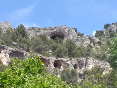 a mountain with three tunnels in the rocks at maison au coeur de Fontaine de Vaucluse, nichée sur le rocher et surplombant la sorgue in Fontaine-de-Vaucluse