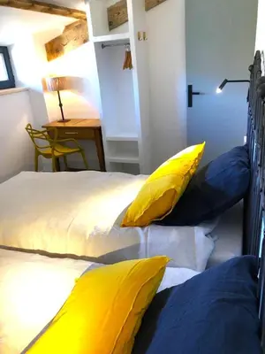 a bedroom with two beds with yellow and blue pillows at Logement calme avec vue sur le Luberon in Saignon