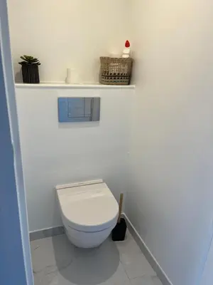 a white bathroom with a toilet and a shelf at Superbe appartement avec balcon et parking in Aix-en-Provence