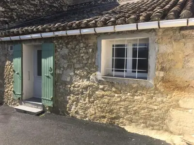 a stone house with green doors and a window at 2 pièces et mezzanine dès 2 nuits in Vedène