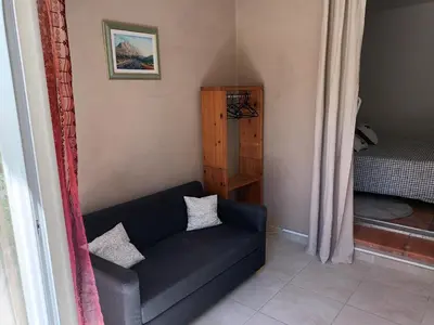 a living room with a black couch and a bed at Chambre raisin 2p, pour 2 nuits max, a 6km du festival de piano de la roque d'anthéron à 100m de la piscine in Rognes