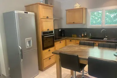 a kitchen with a table and a refrigerator at Le Ribbou in LʼIsle-sur-la-Sorgue