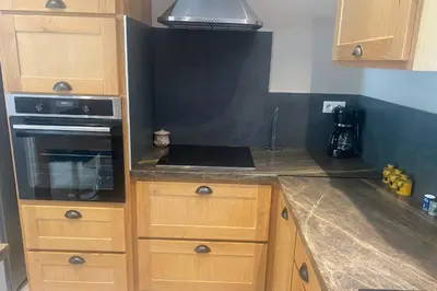 a kitchen with wooden cabinets and a stove top oven at Le Ribbou in LʼIsle-sur-la-Sorgue