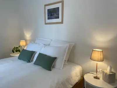 a white bed with two green pillows and two lamps at Le Mas de Caroline in Gargas