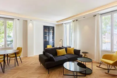 a living room with a black couch and yellow pillows at Appartement exceptionnel avec parking Centre-ville Aix-en-Provence in Aix-en-Provence