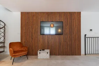 a chair and a television on a wall at Au NÈGO CHIN 105m2 en bord de Sorgue in LʼIsle-sur-la-Sorgue