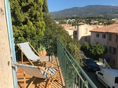 a balcony with chairs and a view of a city at Au petit bonheur in Bédoin