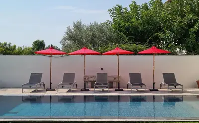 a group of chairs and umbrellas next to a pool at La Tour D'Orgueil in Mallemort