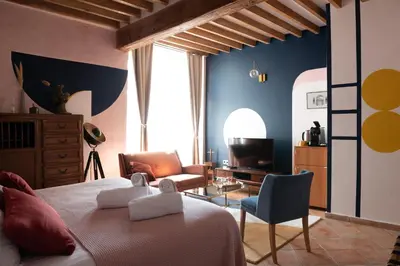 a bedroom with a bed and a chair and a television at La Maison d'en Bas des Seigneurs in Cucuron