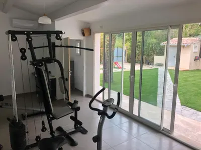 a gym with two tread machines in a room with windows at Au milieu des Piboules de Provence. in LʼIsle-sur-la-Sorgue