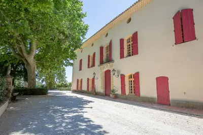 a white building with red doors and a tree at Cosy Loft tarif avec 1 ou 2 chambres 2 ou 4 personnes, vue parc et piscine in Aix-en-Provence