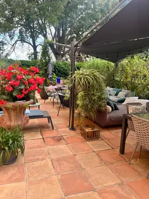 a patio with an umbrella and chairs and flowers at Cosy Loft tarif avec 1 ou 2 chambres 2 ou 4 personnes, vue parc et piscine in Aix-en-Provence