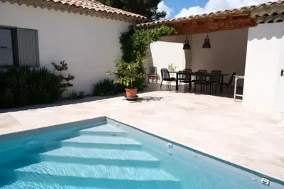 a swimming pool in front of a house at charming vacation rental with heated pool at the foot of the alpilles, in aureille, close to the center of the village on foot, sleeps 6/8 people in provence. in Aureille