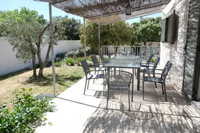 a patio with a table and chairs under a pergola at charming vacation rental with heated pool at the foot of the alpilles, in aureille, close to the center of the village on foot, sleeps 6/8 people in provence. in Aureille